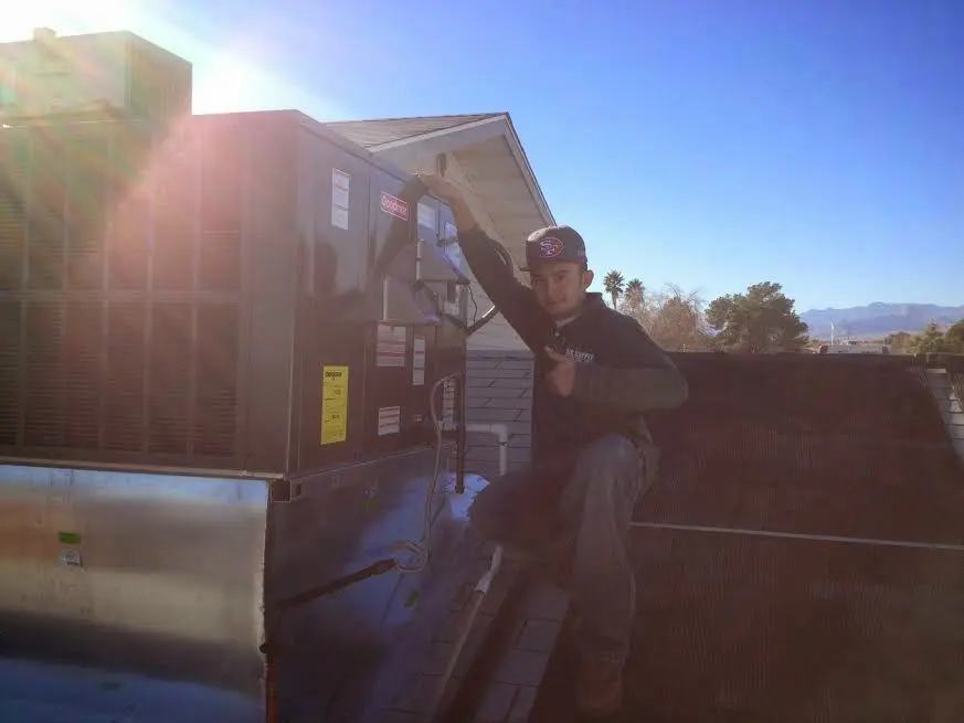 HVAC technician performing Air Duct Cleaning on a rooftop unit in Holdrege